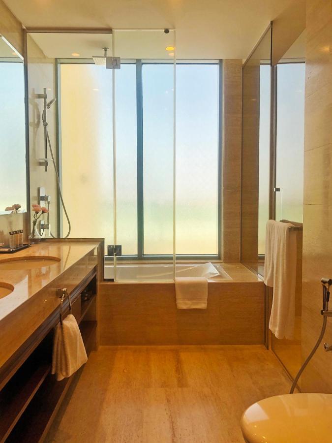 Grand Swiss-Belhotel Waterfront Seef Sanabis Exterior foto The photo features a modern bathroom with a clean and stylish design. It includes a double sink vanity with a wooden countertop and a large mirror. A shower area is visible with a glass wall, allowing for an open feel. There is a bathtub next to a wi